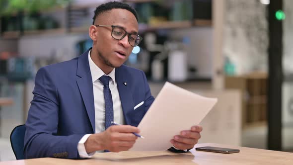 Focused African Businessman Reading Documents in Office 