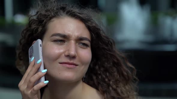 Capricious Smiling Woman Is Talking By Cell Phone Outdoors in City, Closeup Portrait