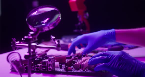 Closeup of Assembling Motherboard in Neon Light Fixing Details for Gadget in Protective Blue Gloves