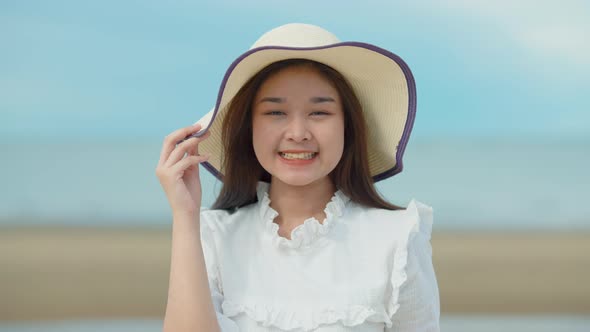 Cute Asian girl walking on the beach by the beach. She turned to smile at the camera.