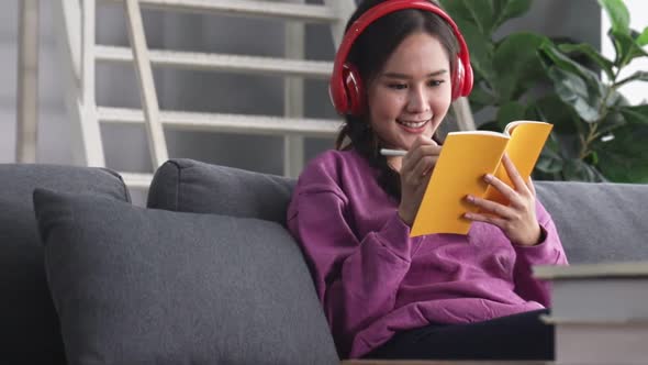 Happy young asian woman relaxing at home sit on sofa holding digital tablet