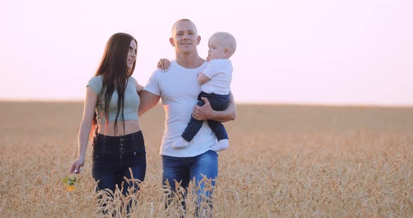 Happy Childhood Family Walking on a Wheat Field at Sunset