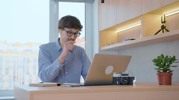 Man works remotely with colleagues at work through a laptop using video communication.