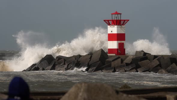 Rough sea breaks over jettty and lighthouse on the coast of Scheveningen, The Hague, The Netherlands