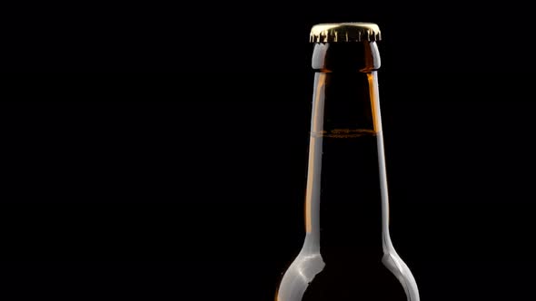 Glass Bottle of Beer Spinning in the Dark on a Black Background