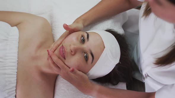 Caucasian woman lying back while beautician gives her a facial