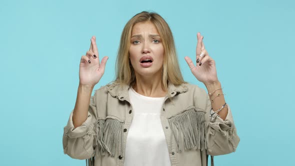 Slow Motion of Hopeful Blond Woman in Stylish Outfit Cross Fingers for Good Luck and Praying