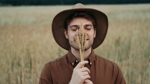 Portrait of Farmer Holding a Spikelet with a Brush of Wheat or Rye in His Hands at Sunset Looking