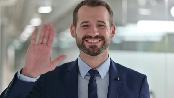 Portrait of Cheerful Businessman Waving at the Camera 