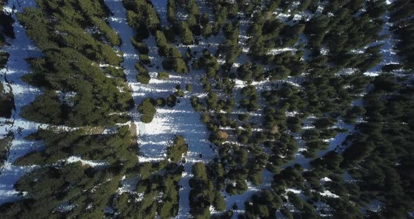 Aerial drone view of a man and woman couple hiking in snow covered mountains in the winter.