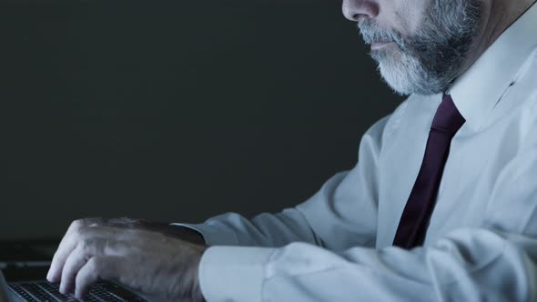 Serious Businessman Using Computer in Dark Office