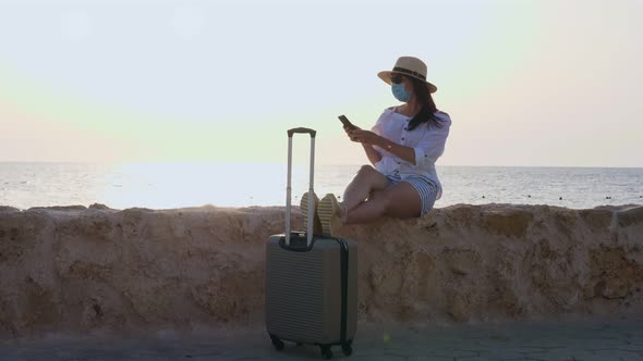 Woman in Protective Mask, Summer Clothes, Sunglasses, Sun Hat and with Travel Suitcase, Luggage