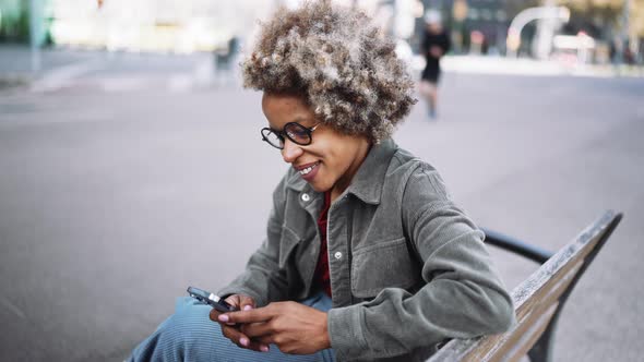 Pensive adult African woman wearing casual clothes typing on mobile