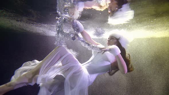 A Girl in A White Christmas Sexy Dress, Which Flutters Tulle, She Is Under Water on A Dark