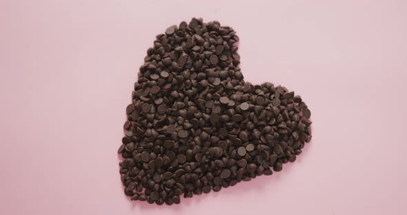 Video of heart formed with chocolate chip and copy space over pink background