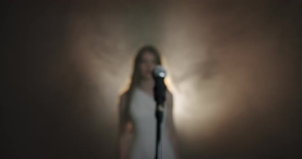 The Girl Singer Approaches the Microphone and Begins To Sing, the Scene in Smoke. Close Up V2