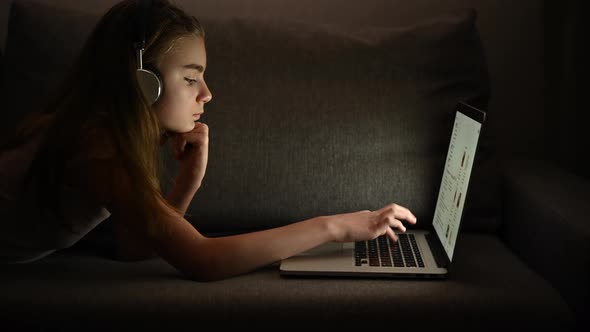 Girl with Headphones and Her Computer Relaxing on Some Bed