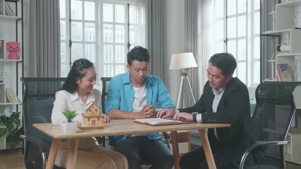 Asian Real Estate Agent Explaining About House Purchase Contract To A Couple