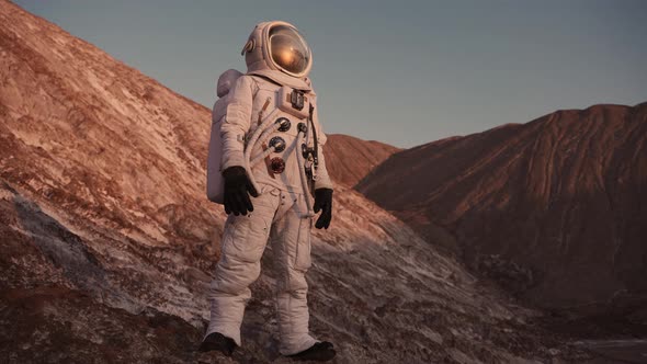 Astronaut Standing on a Rock Opens the Flap of His Helmet and Looks Around