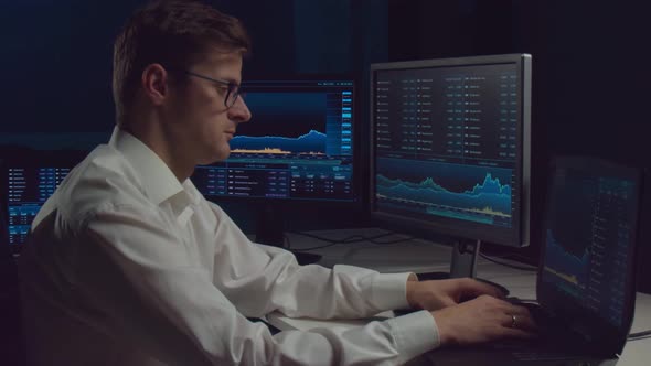 Trader working in office at night using workstation and analysis technology.