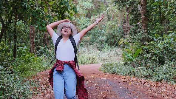 Happy young tourist woman with backpacks in a tropical forest. A female tourist finds a walking path