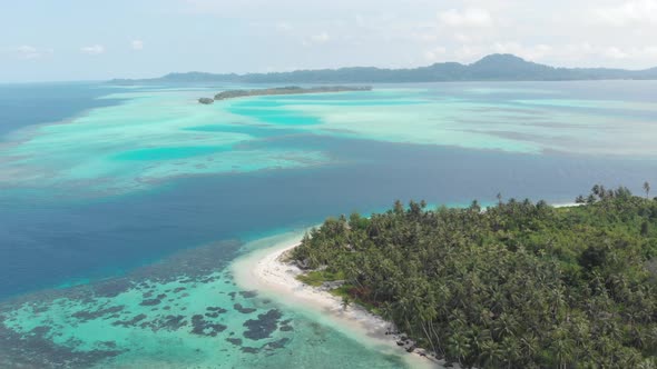 Aerial: flying over tropical island white beach caribbean sea turquoise water coral reef Indonesia