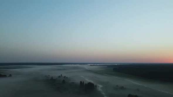 Foggy dawn in the countryside. Foggy river valley and rising sun. Aerial photography.