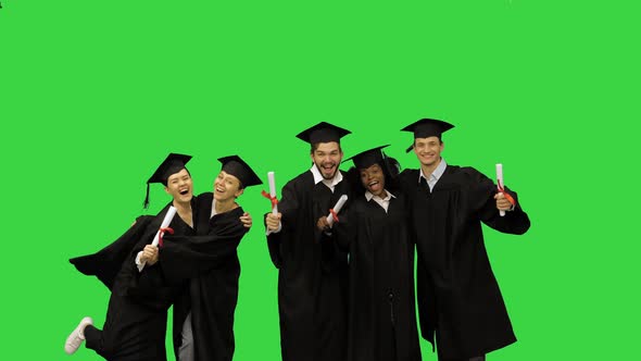 Happy Students in Graduation Gowns Posing for a Picture on a Green Screen Chroma Key