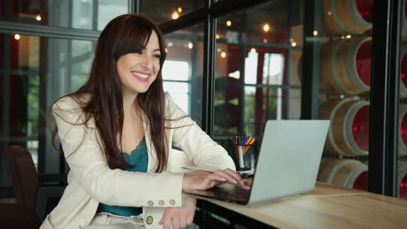 Young Woman Manager Sitting Coworking Office at Workplace in Front of a Laptop