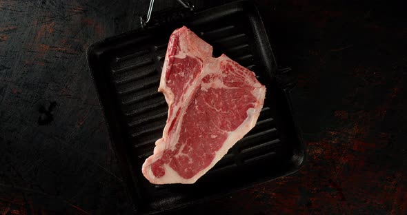 Steak T-bone Raw Beef in a Frying Pan Slowly Rotates. 