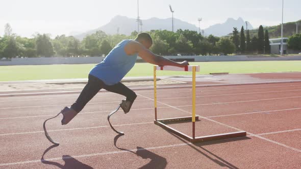 Disabled mixed race man with prosthetic legs stretching with a hurdle