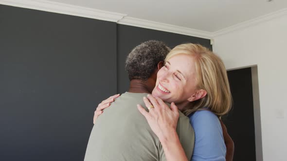 Mixed race senior couple hugging each other at home