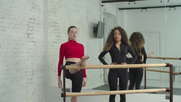 Black Woman Practicing Barre Workout with Trainer at Gym