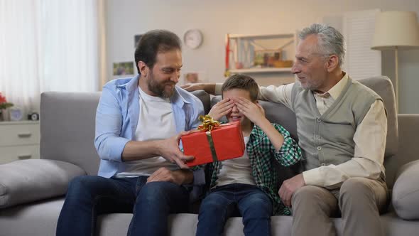 Granddad and Dad Congratulating Preteen Boy, Giving Birthday Present in Box