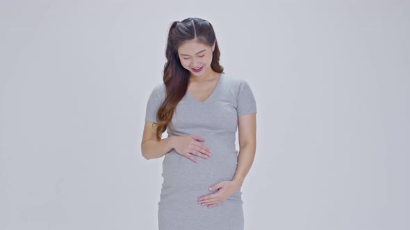Happy Pregnant Woman standing smile and stroking big belly with love