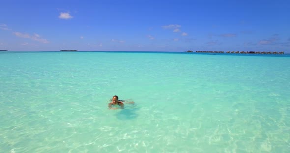 Aerial drone view of a woman floating and swimming on a tropical island.