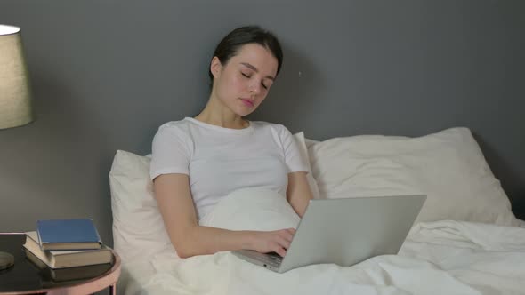 Drowsy Woman with Laptop Falling Asleep in Bed 