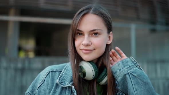 Handsome blonde woman in headphones wearing jeans jacket looking at the camera