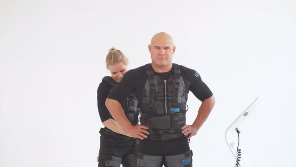 Blonde Female Trainer Helps Man To Attach Electrode on Ems Suit