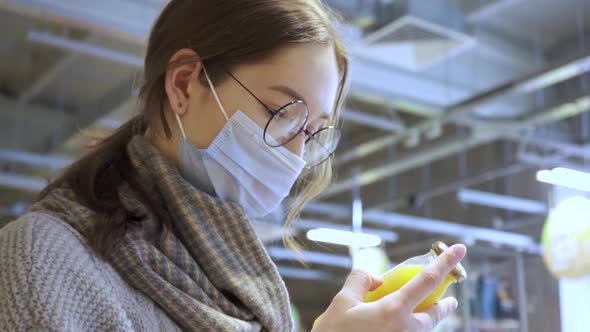 A Young Female Customer Reads the Composition of the Drink on the Juice Bottle