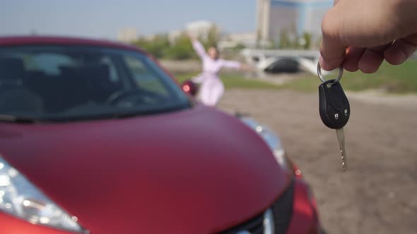 The Girl Snatches the Keys From the Man's Hands and Runs Happily Hugging a New Car