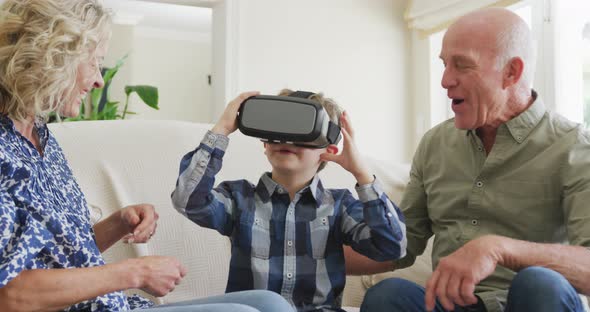 Happy senior caucasian couple with grandson using vr headset in living room