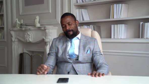 A Sleepy African-American with a Beard and a Stylish Gray Suit. The Businessman Is in a Bright