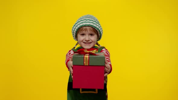 Kid Girl Christmas Elf Santa Helper Giving Present Gift Box To Camera