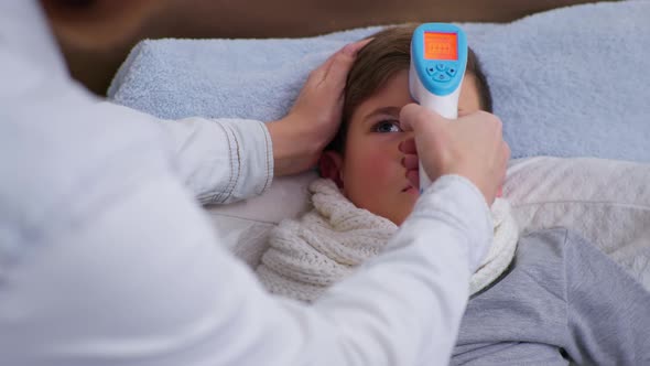 Boy Feeling Unwell Has High Temperature Measured with Noncontact Thermometer in Degrees Celsius