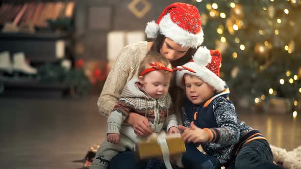 Family Opening Christmas Present in Front of Tree