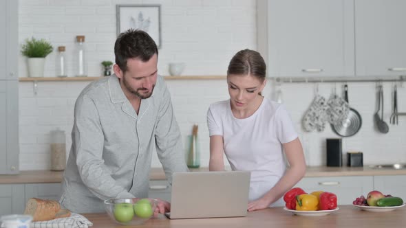 Woman and Man Working on Laptop in Kitchen