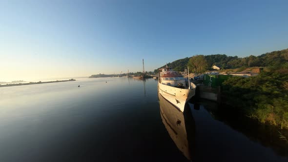 FPV Drone View of Flying Over Water at Dawn Past an Abandoned Ship