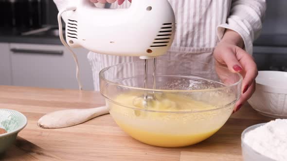 Baker Using Handheld Electric Mixer On Cake Batter. - close up, slider left