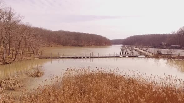 Aerial footage over cat tails crossing a foot bridge at a boat marina on an icy lake during the wint